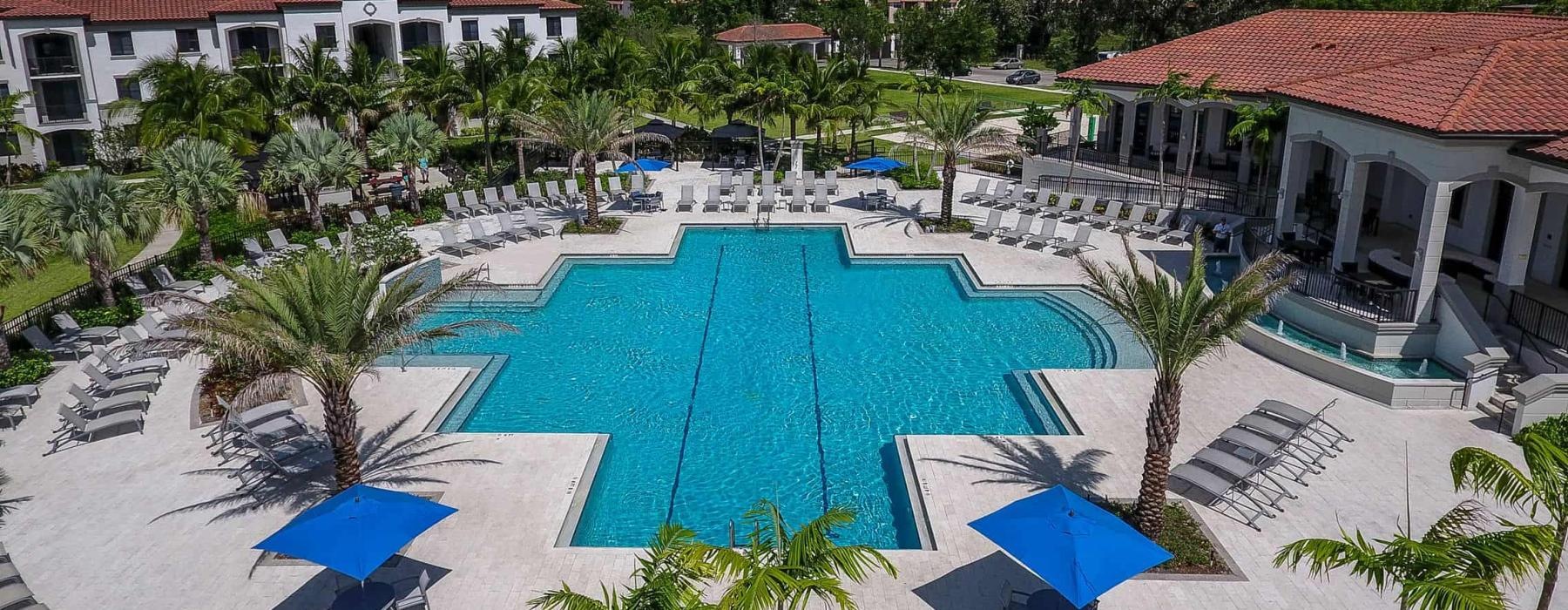 a pool with umbrellas and chairs by a building